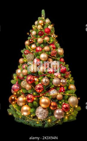 weihnachtsbaum mit goldenen und roten Kugeln auf schwarzem Hintergrund. Stockfoto
