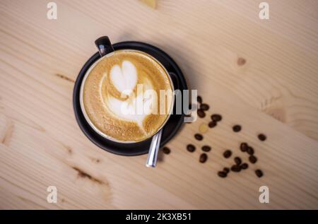Draufsicht auf eine Tasse herzförmigen Kaffee Latte auf einem Holztisch Stockfoto