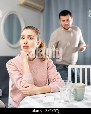 Beleidigte Frau, die zu Hause sitzt, nachdem sie mit ihrem Freund gespuckt hat Stockfoto