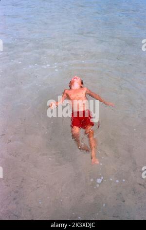 Hochwinkelansicht des jungen Jungen, der auf seinem Rücken im Wasser schwimmt, Bermuda, Toni Frisell Collection, 1956 Stockfoto