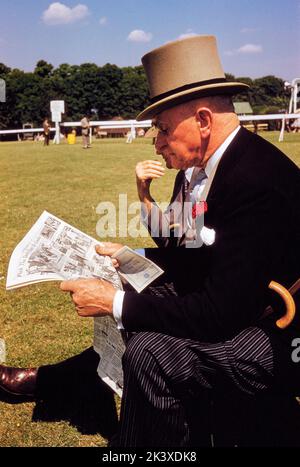 Mann in formeller Kleidung beim Lesen der Zeitung, während er das englische Derby, Epsom Downs Racecourse, Epsom, Surrey, England besuchte, Großbritannien, Toni Frisell Collection, 3. Juni 1959 Stockfoto