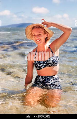 Frau kniet im Wasser am Strand, Hawaii, USA, Toni Frisell Collection, 1957 Stockfoto