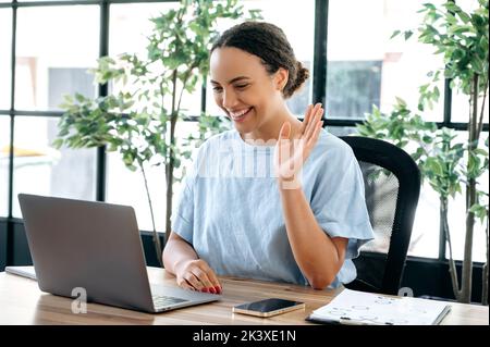 Positive schöne erfolgreiche brasilianerin oder Latino-Frau, sitzt an einem Schreibtisch im Büro, im Gespräch auf einer Videokonferenz mit einem Kollegen oder Kunden, Personalmanager führt ein Interview mit dem Kandidaten Stockfoto