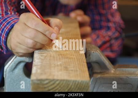 Der Zimmermann in der Werkstatt bereitet eine Schneidebrett vor. Tischlerarbeiter in der Schreinerei. Ein sorgfältiger Experte und sorgfältiger Handwerker, der sich auf die Arbeit konzentriert. Stockfoto