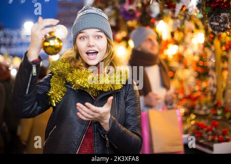 Fröhliche junge weibliche Kauf Dekoration auf der Weihnachtsmesse Stockfoto