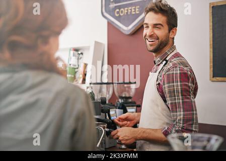 Lockeres Gespräch mit einem Gast. Ein junger Barista, der einen Gast bedient. Stockfoto