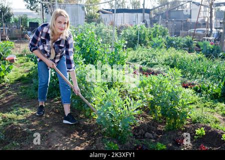 Junge Frau Unkraut mit einer Hacke das Gartenbett Stockfoto