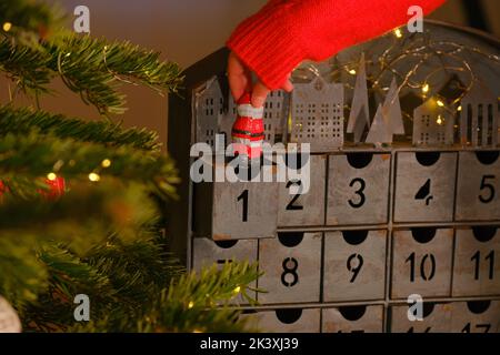 adventskalender.Schokolade weihnachtsmann in der Hand auf weihnachten Adventskalender Hintergrund. Weihnachtstraditionen und Symbole. Geschenke und Überraschungen für Stockfoto