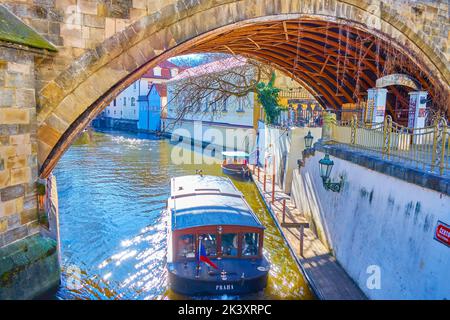 Ein kleines Touristenboot fährt unter der Karlsbrücke im Prager Stadtteil Mala Strana Stockfoto