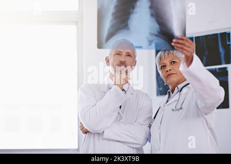 Achten Sie auf Unregelmäßigkeiten. Zwei Ärzte betrachten zusammen eine Röntgenaufnahme. Stockfoto