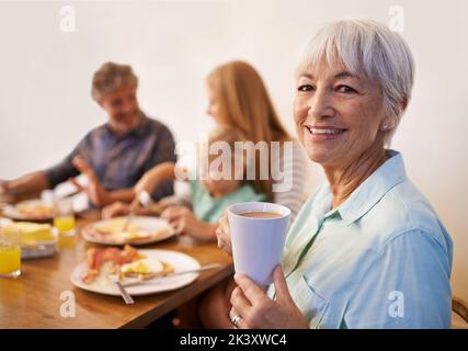 Genießen Sie ein köstliches Frühstück mit der Familie. Ein beschnittenes Porträt einer glücklichen, reifen Frau, die mit ihrer Familie frühstückt. Stockfoto