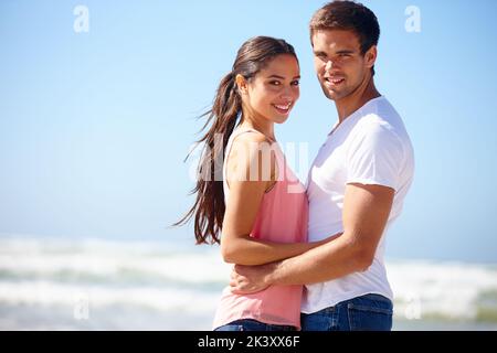 Liebe lässt Ihre Seele aus ihrem Versteck kriechen. Ein romantisches Paar, das an einem Sommertag am Strand Zuneigung zeigt. Stockfoto