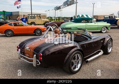 Ein Mann fährt einen braunen Shelby AC 427 Cobra Replik-Sportwagen vor der Worldwide Auctioneers 2022 Auburn Auction in Auburn, Indiana, USA, in die Reihe. Stockfoto