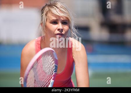 Shes wird ein Tennisstar. Ein junger Tennissportler mitten im Set. Stockfoto