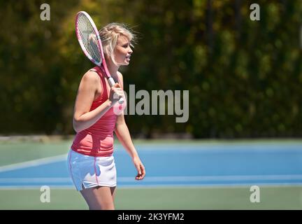 Shes wird ein Tennisstar. Ein junger Tennissportler mitten im Set. Stockfoto