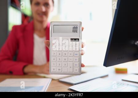 Geschäftsfrau hält Rechner in der Hand mit der Nummer einhundert im Büro Stockfoto