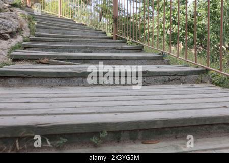 Holztreppe, die an sonnigen Tagen weit über den grasbewachsenen Hang führt Stockfoto