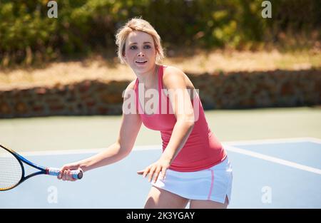 Shes wird ein Tennisstar. Ein junger Tennissportler mitten im Set. Stockfoto