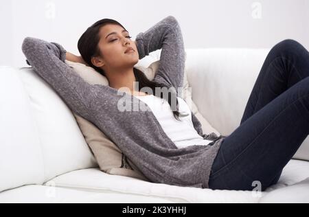 Aufladen der Batterien. Eine junge Frau, die ein Nickerchen auf ihrem Sofa macht. Stockfoto