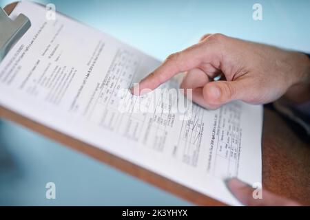 Überprüfung der Einnahmen des Unternehmens. Zugeschnittenes Bild eines Geschäftsmanns, der auf ein Finanzdokument in einer Zwischenablage zeigt. Stockfoto