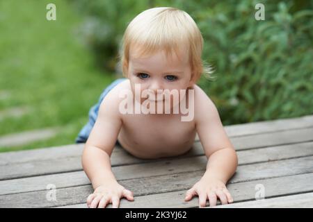 Hes ein neugieriger Junge. Ein süßer kleiner Junge, der draußen kriecht. Stockfoto