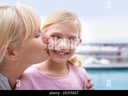 Weich wie ein Mutterküss. Eine liebevolle Mutter, die ihrer Tochter einen Kuss auf die Wange gab. Stockfoto