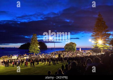 Eine große Menschenmenge traf sich zu einer Parade am ANZAC Day in der Dämmerung in Mount Maunganui, Neuseeland Stockfoto