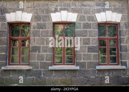 Ein altes klassisches Steinhaus mit Fenstern. Kalkige Steinwände und Fensterstrukturen. Hochwertige Fotos Stockfoto