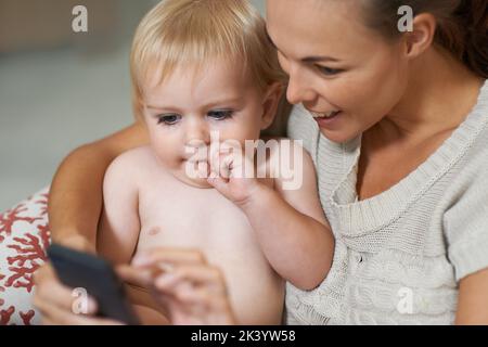 Sehen Sie sich das an...Eine Mutter zeigt ihrem Jungen etwas auf ihrem Handy. Stockfoto