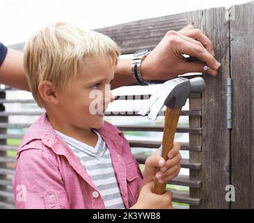 Vater und Sohn Zeit. Netter kleiner Junge, der seinem Vater hilft und einen Hammer hält. Stockfoto