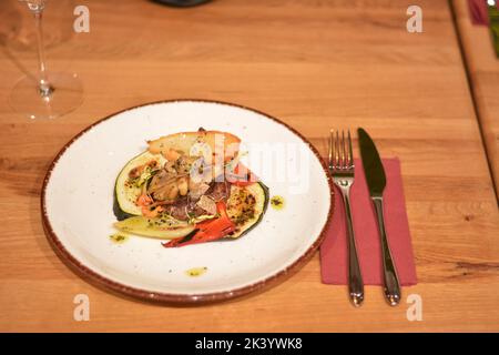 Rindersteak auf einem Bett aus sautiertem Gemüse und gegrillten Zucchini, Weizenkeimen und Toast. Stockfoto