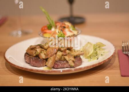 Köstliches Rindersteak, bedeckt mit sautierten Pilzen. Garnieren Sie mit Gratin-Kartoffeln und Weizenkeimen. Stockfoto