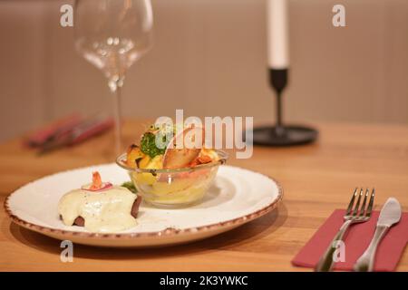 Schweinekotelett mit weißer Soße und Keilen Kartoffeln und Weizenkeime und Toast. Stockfoto