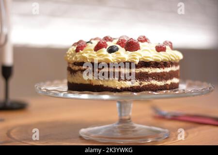 Kakaokuchen, Vanillecreme und Beeren. Stockfoto