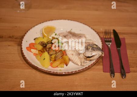 Gebackener Fisch mit Zitrone, Kartoffeln, Karotten, Brokkoli und Pilzen. Stockfoto