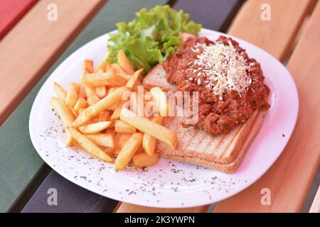 Bruschetta mit Hackfleisch und Käse, pommes Frites und Salat. Stockfoto