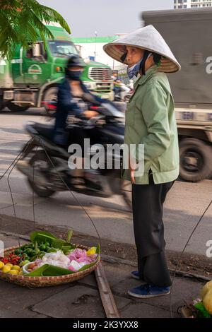 Vietnamesischer Straßenhändler mit Bambushut, der Lebensmittel von einer Fahrradtasche auf der Straße, Hai Phong, Vietnam, verkauft Stockfoto