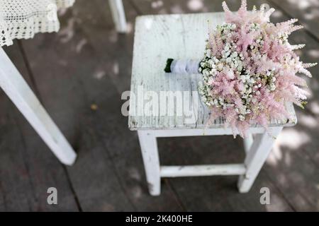 Ein wunderschöner Braut-Hochzeitsstrauß aus verschiedenen bunten Blumen, der vor einem weichen natürlichen Hintergrund im Freien platziert ist und elegante Details zur Schau stellt. Stockfoto