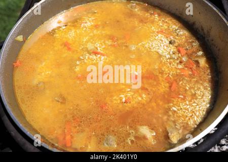 Zubereitung Pilaf mit Lamm in Kessel auf Feuer Stockfoto