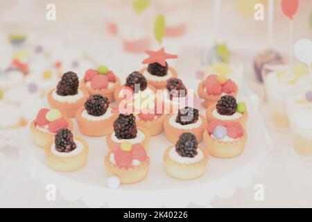 Minitörtchen mit Vanillecreme, verziert mit Himbeeren und Brombeeren Stockfoto