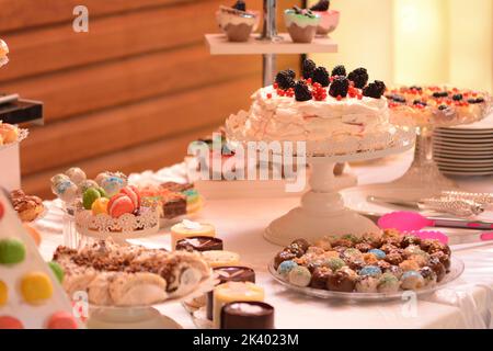 Kuchen mit Baiser, Brombeeren und roter Stachelbeere; Fondant mit Kakaoglasur und Sirupkuchen Stockfoto