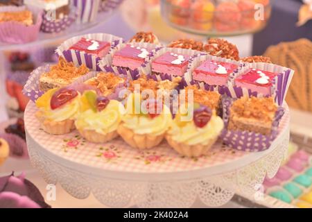 Teller mit verschiedenen Kuchen: Kuchen mit Sahnetorten und Erdbeergelee, Nußnuss- und knuspriger Karamellkuchen und Minitörtchen mit Vanillecreme Stockfoto