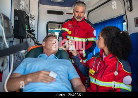 Das paramedizinische Personal bereitet den Mann auf den Infusionstropfen vor Stockfoto