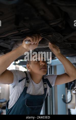 Fokussierter junger Mechaniker, der das Kundenfahrzeug repariert Stockfoto