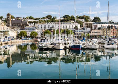 Die Boote, die im Binnendock des Hafens festgemacht wurden, spiegeln sich im ruhigen Wasser wider. Torquay, Devon, England, Großbritannien Stockfoto
