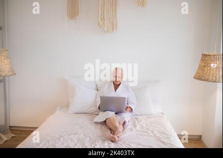Freiberuflerin, die ihren Laptop im Schlafzimmer benutzt Stockfoto