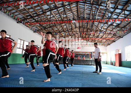 (220929) -- ZHENGZHOU, 29. September 2022 (Xinhua) -- Li Yinggang (R) unterrichtet Schüler während eines Kampfkunstunterrichts an der Shaolin Tagou Kampfkunstschule in Songshan, der zentralchinesischen Provinz Henan, 6. Juli 2022. Der 25-jährige Li Yinggang ist Coach an der Shaolin Tagou Martial Arts School in Songshan, der zentralchinesischen Provinz Henan. Im Alter von 9 Jahren begann er mit der Kampfkunst und wechselte 3 Jahre später in den freien Kampf. Seit seinem 16. Lebensjahr nimmt Li an den professionellen Freikampfwettbewerben Teil und gewann mehrmals die Titel nationaler und internationaler Veranstaltungen, darunter auch Stockfoto