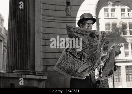 Ein altmodischer Geschäftsmann, der eine brennende Zeitung in der Hand hält. Stockfoto