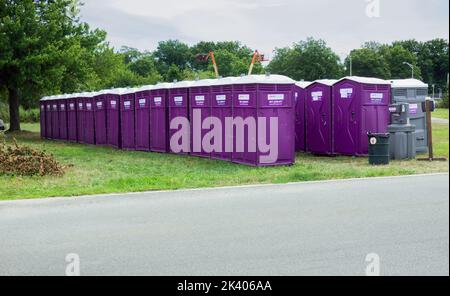 32 lila tragbare Toiletten im Flushing Meadows Corona Park am Wochenende der jährlichen Drachenbootrennen. In Queens, New York City. Stockfoto