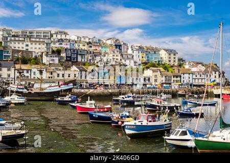 Farbenfrohe Häuser und Geschäfte mit Blick auf den Innenhafen und kleinen Booten, die vor Anker liegen. Brixham, Devon, England, Großbritannien Stockfoto